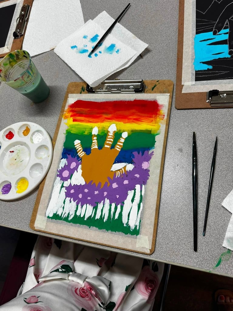 Hands-on art workshop Green Thumb Initiative participant painting a colorful handprint artwork